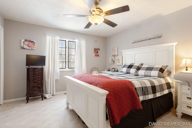 bedroom with ceiling fan, baseboards, a textured ceiling, and light colored carpet