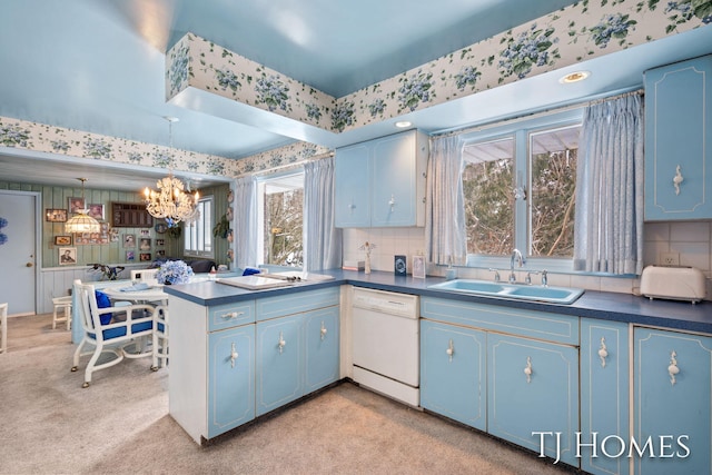 kitchen featuring a sink, dishwasher, dark countertops, decorative light fixtures, and wallpapered walls