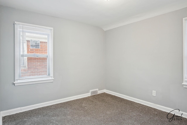 empty room with carpet flooring, visible vents, and baseboards