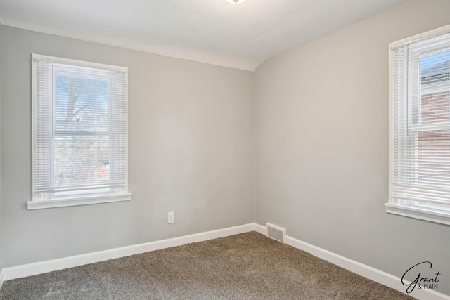 carpeted empty room featuring visible vents and baseboards