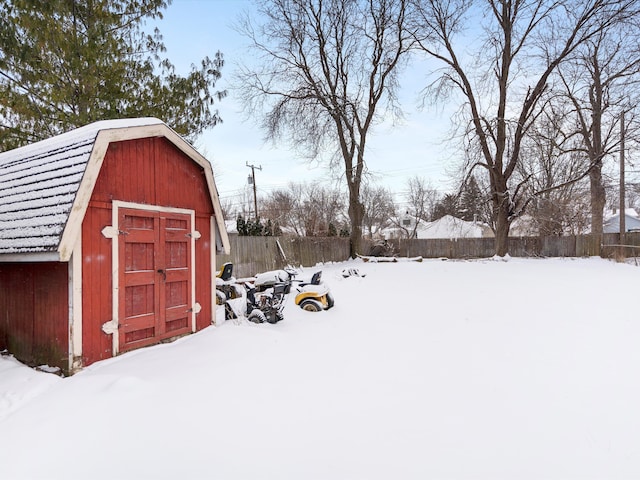 snow covered structure featuring fence and a shed