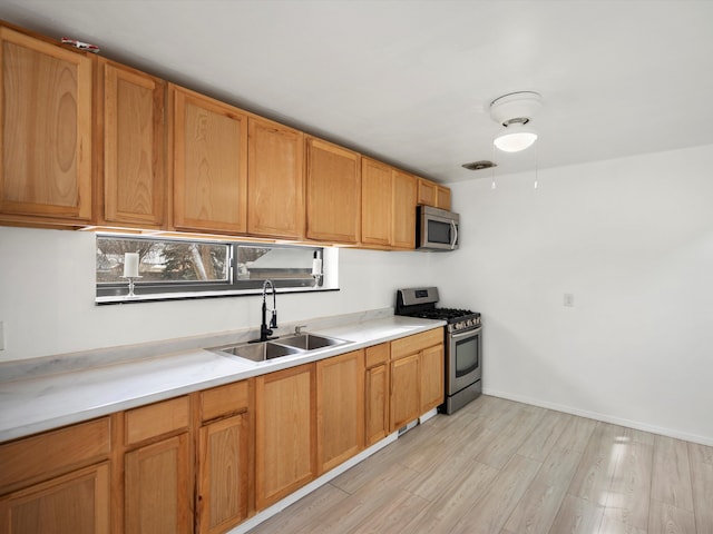 kitchen featuring visible vents, appliances with stainless steel finishes, light countertops, light wood-style floors, and a sink