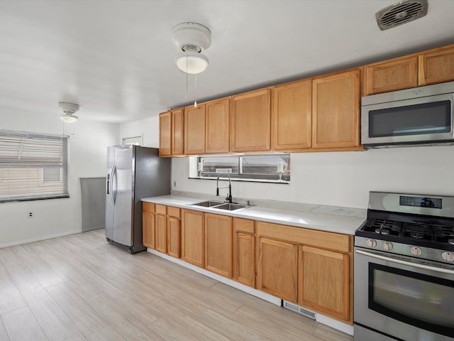 kitchen featuring visible vents, stainless steel appliances, light countertops, light wood-style floors, and a sink