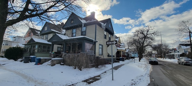 view of snow covered exterior with a chimney and a residential view