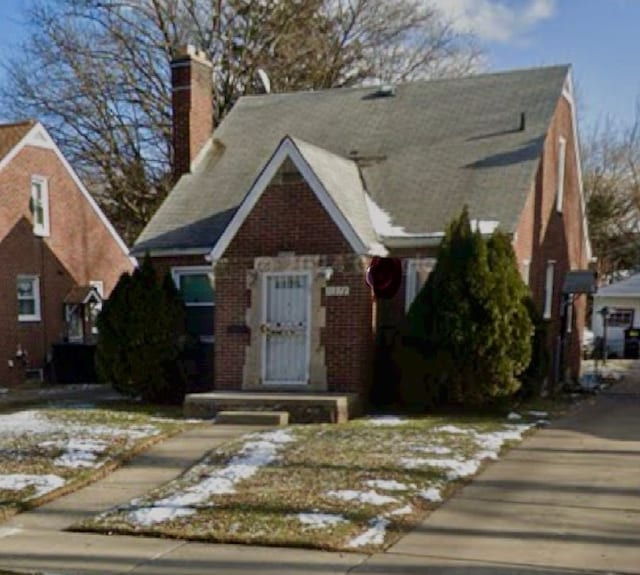 view of front facade with brick siding and a chimney