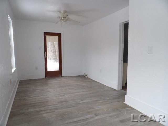 spare room featuring ceiling fan, baseboards, and wood finished floors