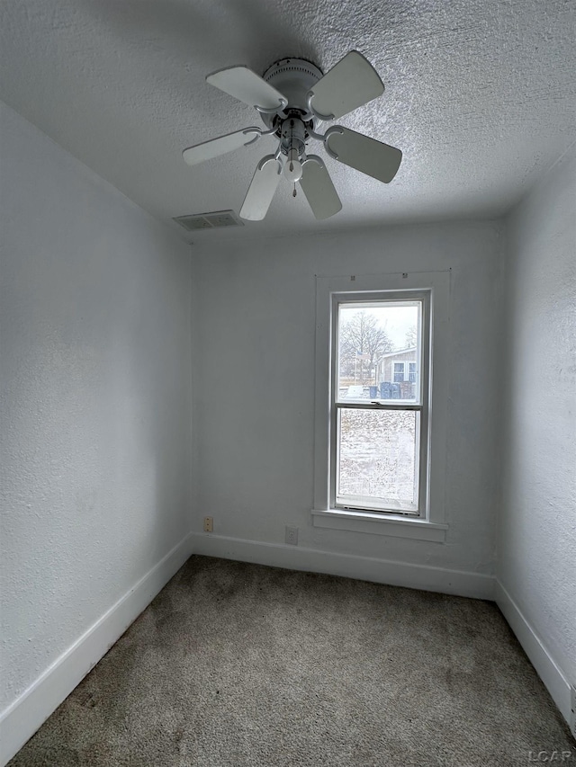 unfurnished room featuring baseboards, carpet, visible vents, and a textured ceiling