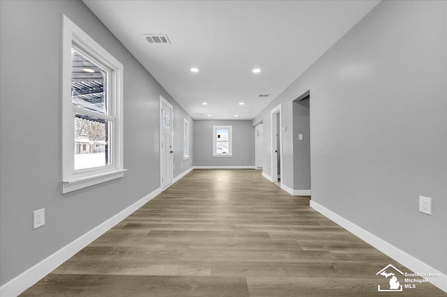 hallway with visible vents, baseboards, wood finished floors, and recessed lighting