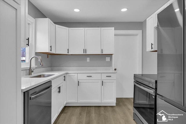 kitchen with a sink, white cabinetry, stainless steel appliances, and light countertops