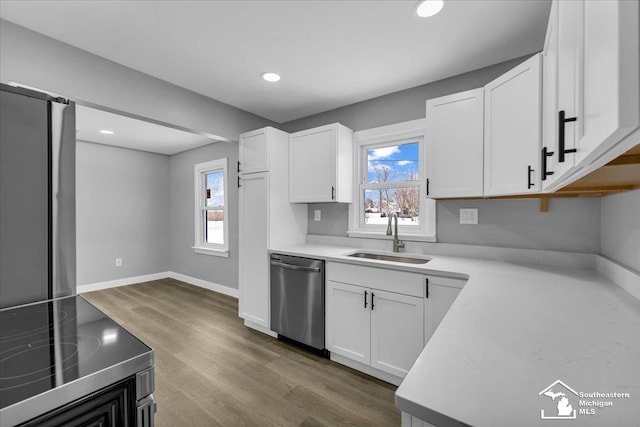 kitchen featuring electric stove, light countertops, stainless steel dishwasher, white cabinetry, and a sink