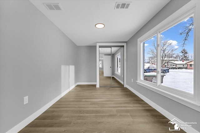 hall with baseboards, visible vents, and wood finished floors