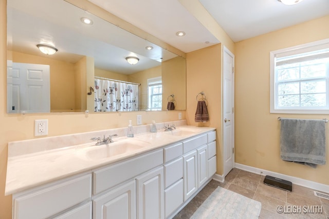 bathroom featuring recessed lighting, a sink, baseboards, and double vanity