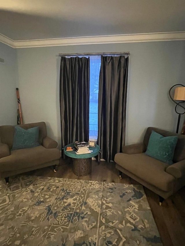 sitting room with ornamental molding and dark wood-style flooring