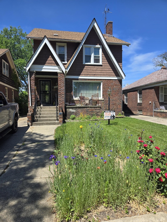 view of front of home with covered porch, brick siding, and a chimney