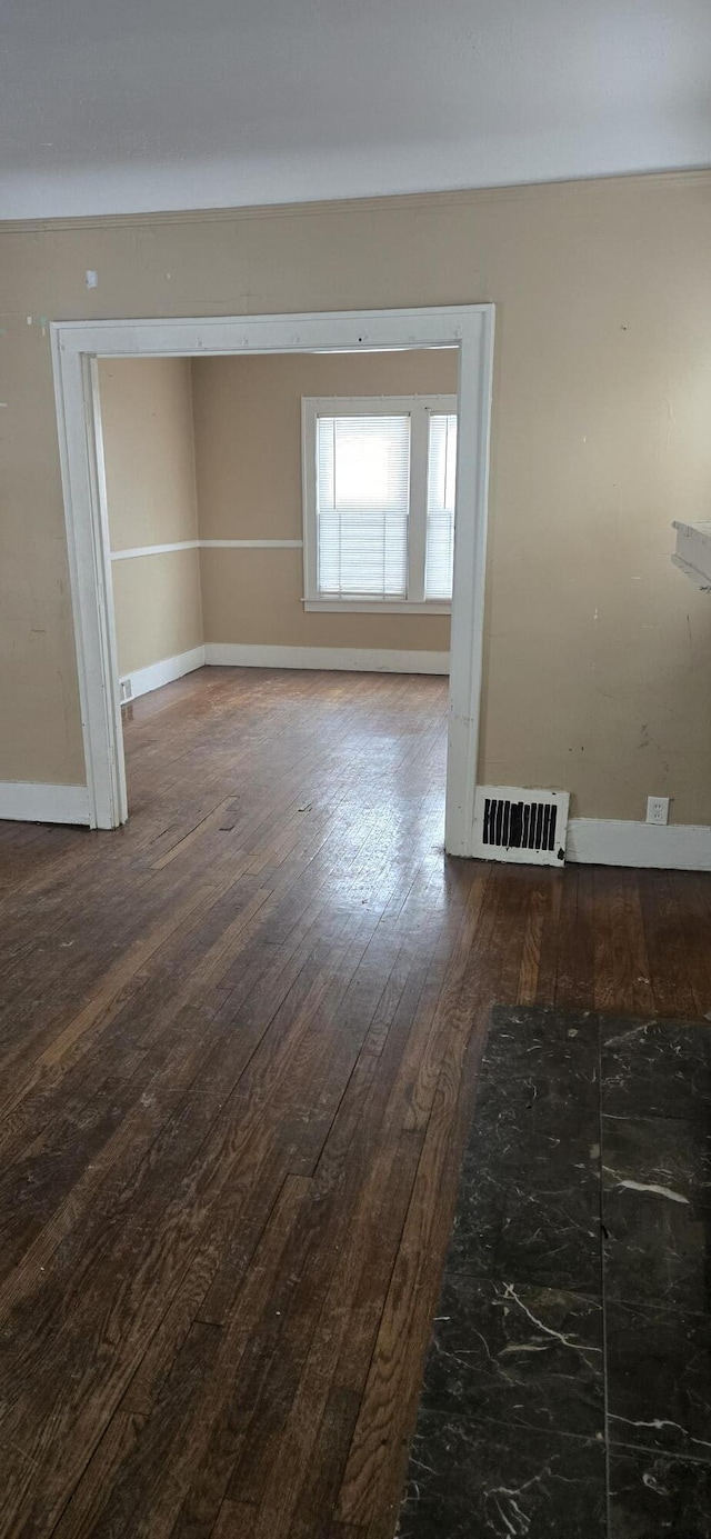 spare room featuring wood finished floors, visible vents, and baseboards