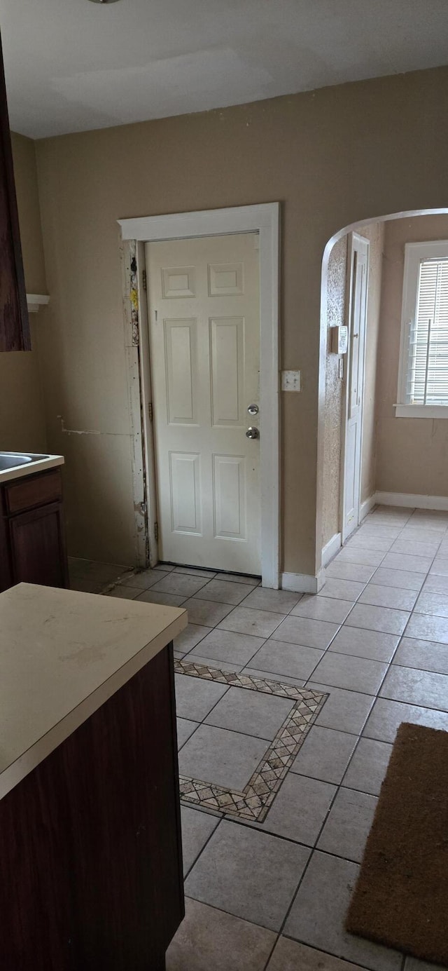 interior space with light tile patterned floors, baseboards, and arched walkways