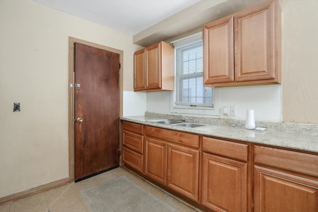 kitchen with light tile patterned flooring, a sink, and baseboards