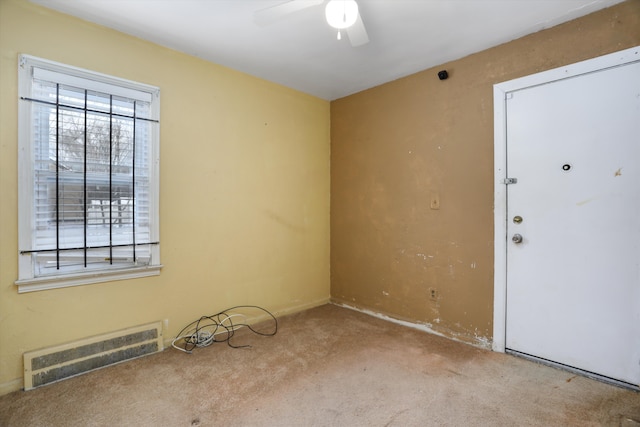 spare room featuring visible vents, ceiling fan, and light carpet