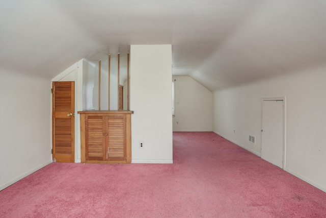 additional living space featuring visible vents, vaulted ceiling, light carpet, and baseboards