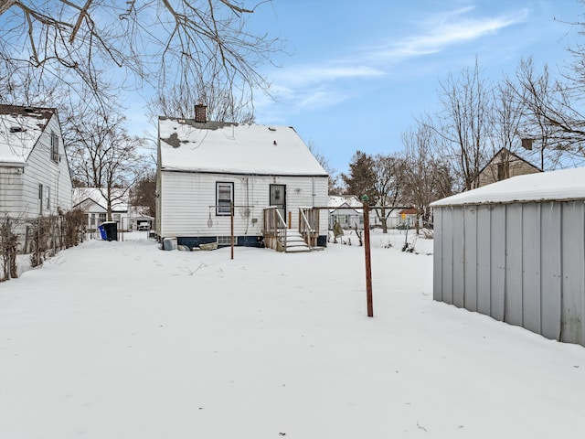 snow covered rear of property with a chimney