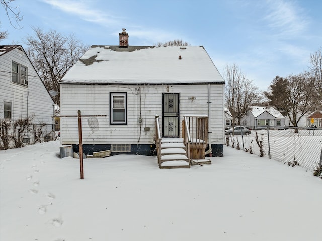 snow covered property featuring a chimney and fence