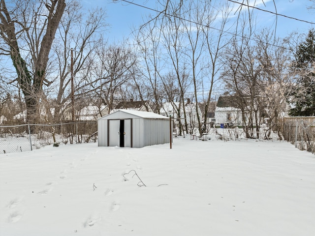 snowy yard with an outbuilding, a storage shed, and fence