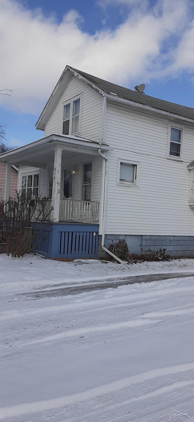 snow covered property featuring covered porch