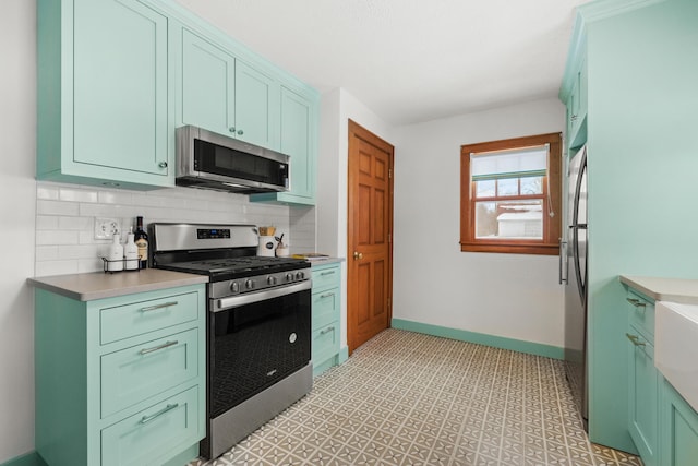 kitchen featuring baseboards, stainless steel appliances, backsplash, and light countertops