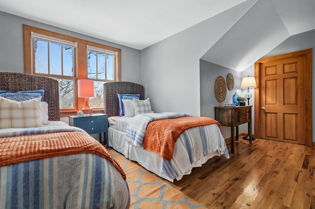 bedroom featuring light wood finished floors and vaulted ceiling