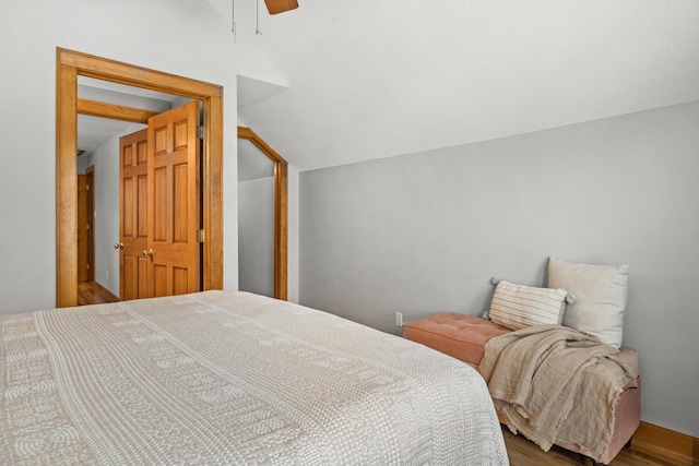 bedroom featuring lofted ceiling, a ceiling fan, and wood finished floors