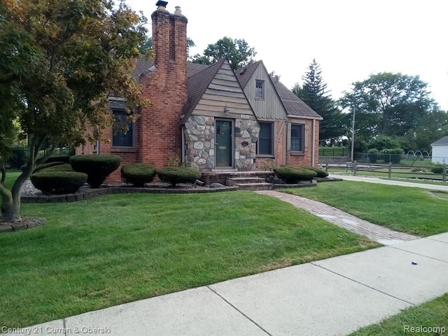 view of front facade with stone siding, a chimney, a front lawn, and brick siding