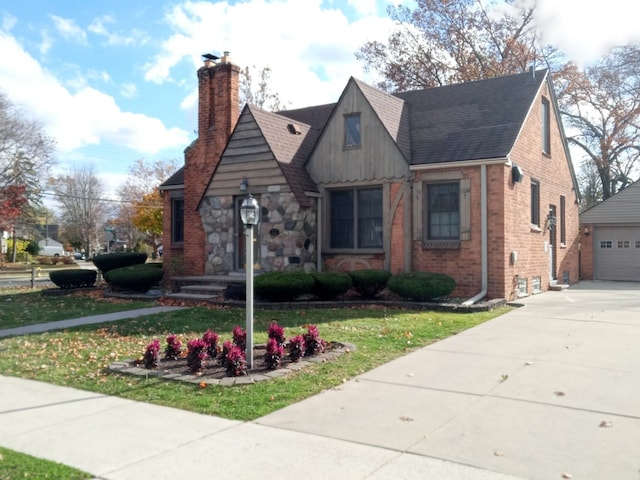 view of front of house featuring a garage, brick siding, a shingled roof, a chimney, and a front yard