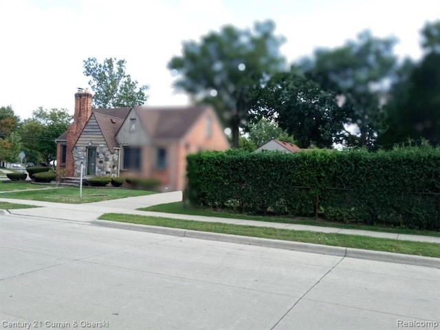 view of front of property with stone siding, a front lawn, and a chimney