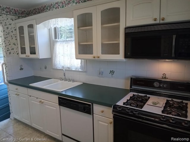 kitchen featuring dark countertops, glass insert cabinets, white cabinetry, a sink, and black appliances