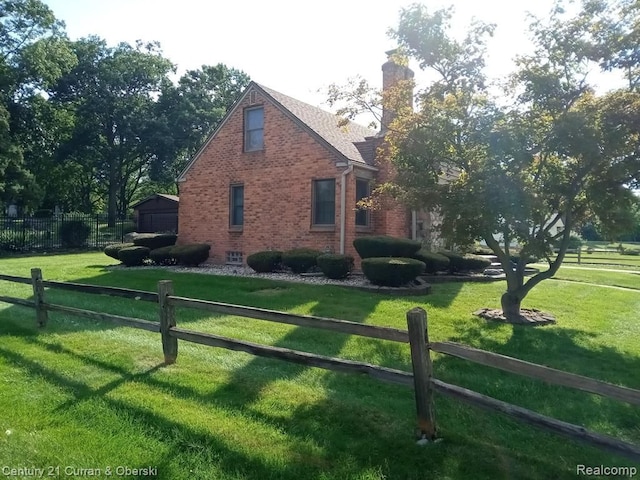 view of home's exterior with a chimney, fence, a lawn, and brick siding