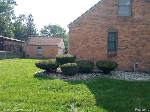 view of home's exterior featuring a garage, brick siding, a lawn, and fence