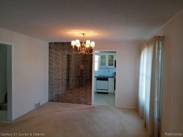 unfurnished dining area featuring light colored carpet, visible vents, and a notable chandelier