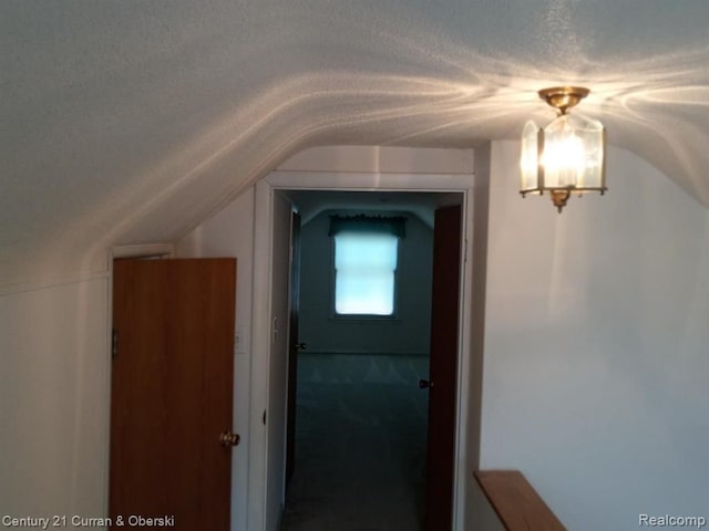 corridor featuring a textured ceiling and lofted ceiling