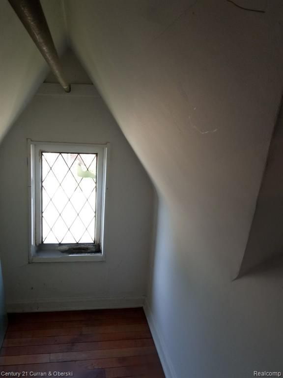 additional living space with dark wood-style floors, baseboards, and vaulted ceiling