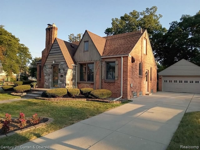 view of front facade with brick siding, an outdoor structure, a detached garage, a front lawn, and a chimney