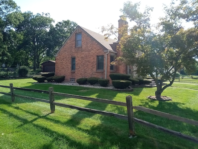 view of side of property featuring brick siding, a lawn, a chimney, and fence