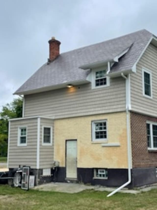 back of property featuring a chimney and a yard