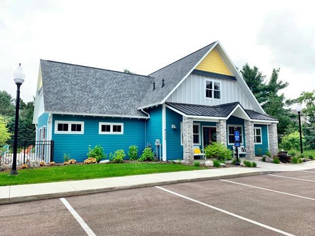 view of front of property with uncovered parking, a standing seam roof, fence, and roof with shingles