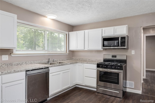 6291 Edmund St, Romulus, MI 48174 - kitchen featuring appliances with stainless steel finishes, dark wood-type flooring, white cabinets, and a textured ceiling