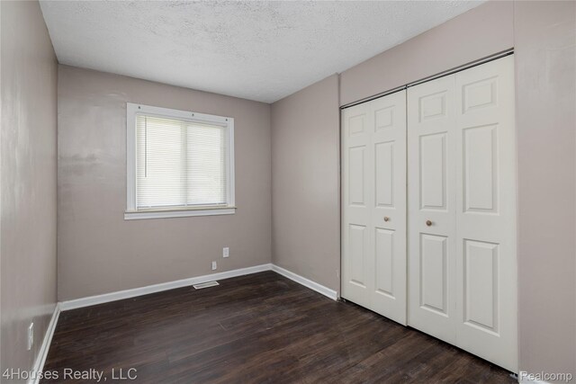 6291 Edmund St, Romulus, MI 48174 - unfurnished bedroom with dark wood-type flooring, a textured ceiling, and a closet