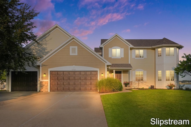 traditional-style home featuring a front yard, concrete driveway, and an attached garage