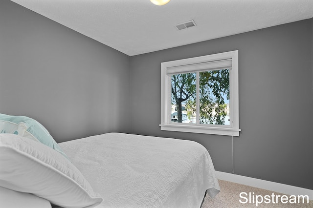 carpeted bedroom featuring visible vents, a textured ceiling, and baseboards