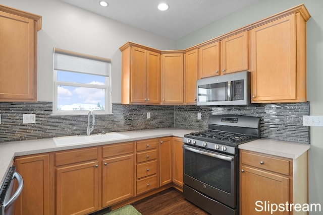 kitchen featuring stainless steel appliances, dark wood-type flooring, a sink, and light countertops