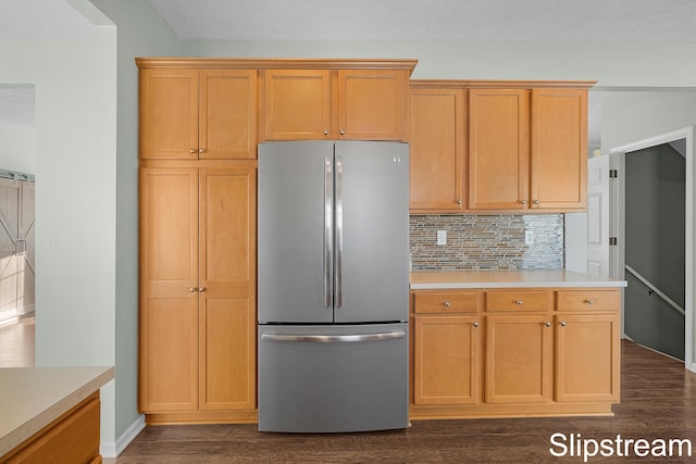 kitchen with light countertops, dark wood-type flooring, freestanding refrigerator, and tasteful backsplash