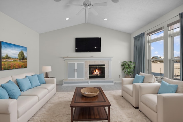 living room with ceiling fan, light colored carpet, a fireplace, baseboards, and vaulted ceiling